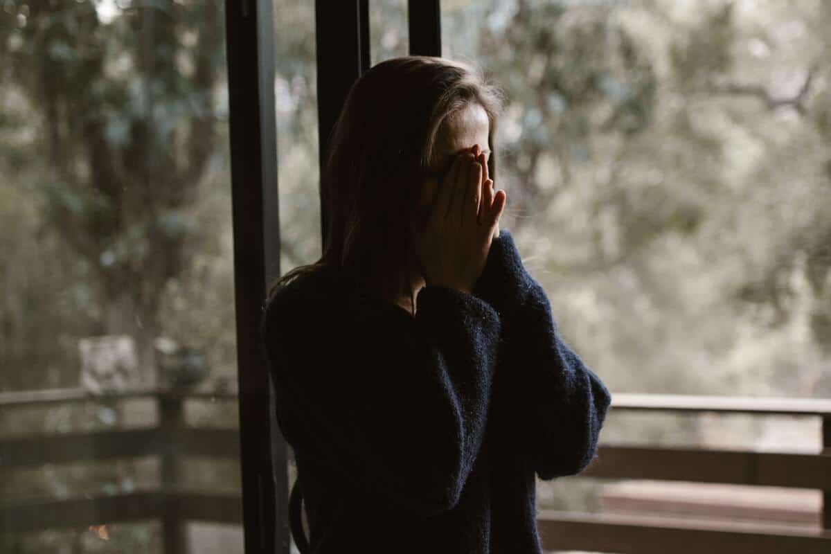 a young woman holding her hands to her face and crying because she is in a toxic relationship