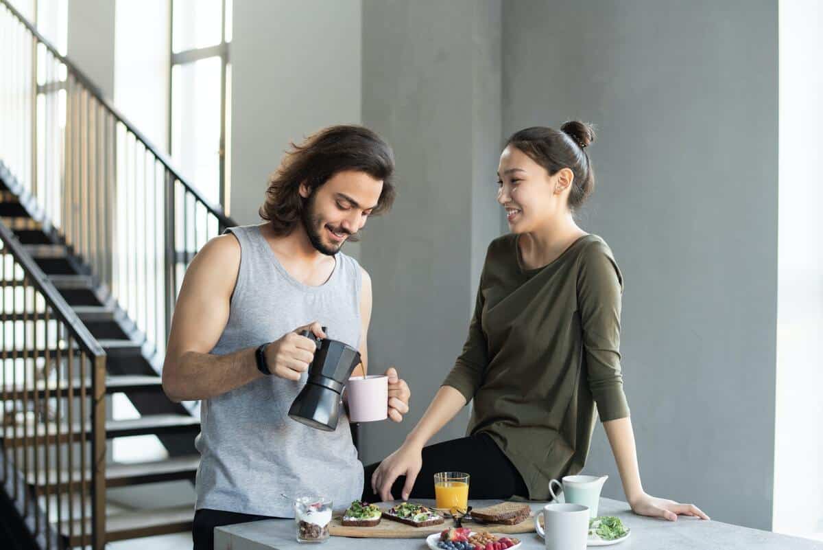 a happy young couple showing how good it is when you understand men. Man pouring coffee and woman watching 